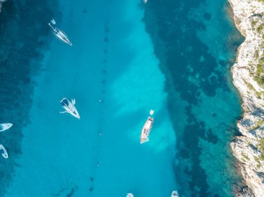 Akdeniz 'de turkuaz safirli sularla dolu tropikal plaja yanaşmış bir teknenin kuş bakışı dronu.