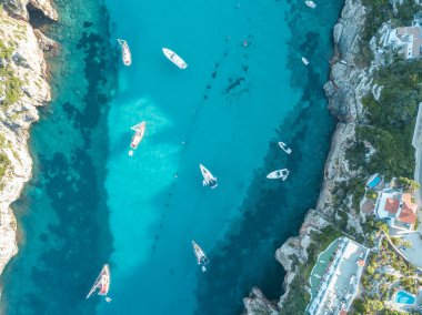 Akdeniz 'de turkuaz safirli sularla dolu tropikal plaja yanaşmış bir teknenin kuş bakışı dronu.