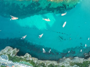 Akdeniz 'de turkuaz safirli sularla dolu tropikal plaja yanaşmış bir teknenin kuş bakışı dronu.