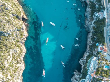Akdeniz 'de turkuaz safirli sularla dolu tropikal plaja yanaşmış bir teknenin kuş bakışı dronu.