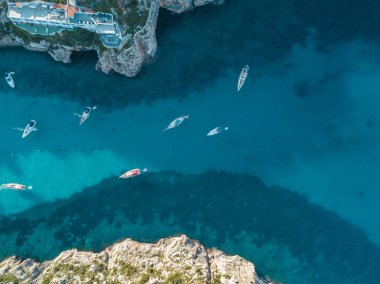 Akdeniz 'de turkuaz safirli sularla dolu tropikal plaja yanaşmış bir teknenin kuş bakışı dronu.