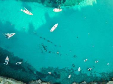 Akdeniz 'de turkuaz safirli sularla dolu tropikal plaja yanaşmış bir teknenin kuş bakışı dronu.