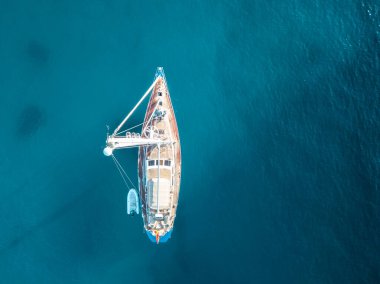 Akdeniz 'de turkuaz safirli sularla dolu tropikal plaja yanaşmış bir teknenin kuş bakışı dronu.