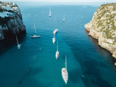 Akdeniz 'de turkuaz safirli sularla dolu tropikal plaja yanaşmış bir teknenin kuş bakışı dronu.