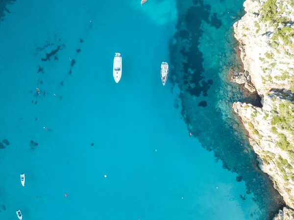 Akdeniz 'de turkuaz safirli sularla dolu tropikal plaja yanaşmış bir teknenin kuş bakışı dronu.
