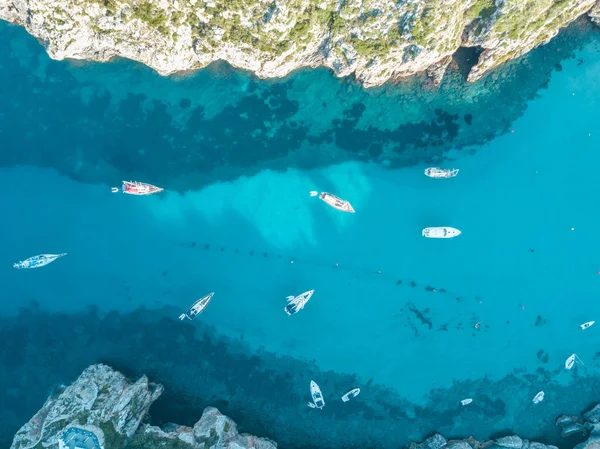 Akdeniz 'de turkuaz safirli sularla dolu tropikal plaja yanaşmış bir teknenin kuş bakışı dronu.