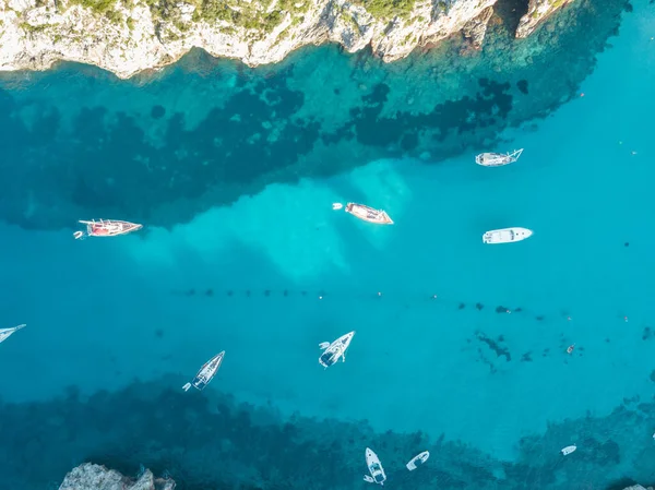Akdeniz 'de turkuaz safirli sularla dolu tropikal plaja yanaşmış bir teknenin kuş bakışı dronu.