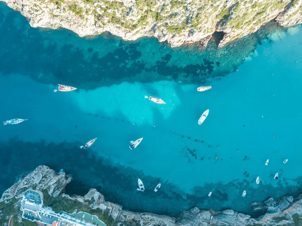 Akdeniz 'de turkuaz safirli sularla dolu tropikal plaja yanaşmış bir teknenin kuş bakışı dronu.
