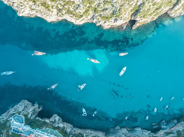 Akdeniz 'de turkuaz safirli sularla dolu tropikal plaja yanaşmış bir teknenin kuş bakışı dronu.