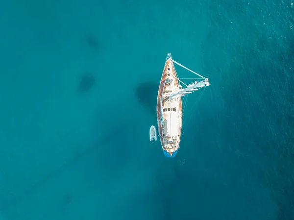 Akdeniz 'de turkuaz safirli sularla dolu tropikal plaja yanaşmış bir teknenin kuş bakışı dronu.