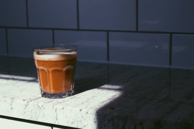 Koyu kırsal arka planda kalın köpüklü bir bardak taze kahve, siyah dokuda espresso americano kahverengi şeker ve kahve çekirdekli kaşık, dikey kopya alanı