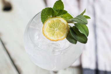 Alkol içki (cin tonik kokteyl) limon, biberiye ve rustik siyah taş tablo, kopya alanı, buza üst görünüm. Limonlu buzlu içecek.