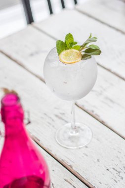 Alkol içki (cin tonik kokteyl) limon, biberiye ve rustik siyah taş tablo, kopya alanı, buza üst görünüm. Limonlu buzlu içecek.