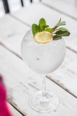 Alkol içki (cin tonik kokteyl) limon, biberiye ve rustik siyah taş tablo, kopya alanı, buza üst görünüm. Limonlu buzlu içecek.