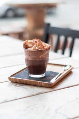 Kahve fincanda, kafenin ahşap masasında, ışıklandırma arka planında.