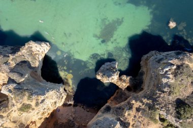 Ponta da Piedade, Portekiz, Algarve 'deki Lagos yakınlarında kayaların üzerinde. Ponta da Piedade, Algarve bölgesi, Portekiz. Plaj Turistleri Şemsiyeler