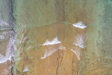 Kumsal ve dalgalar yukarıdan görünüyor. Turkuaz su arka planı. Havadan gelen yaz deniz manzarası. İHA 'nın üst görüntüsü. Seyahat konsepti ve fikri
