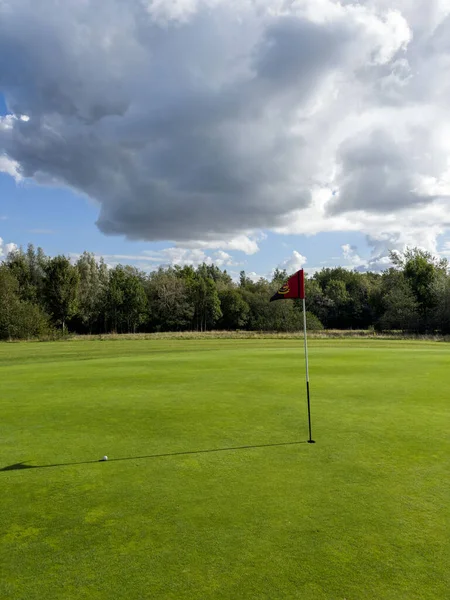 Flag and the hole at golf club blue sky summers day with some clouds