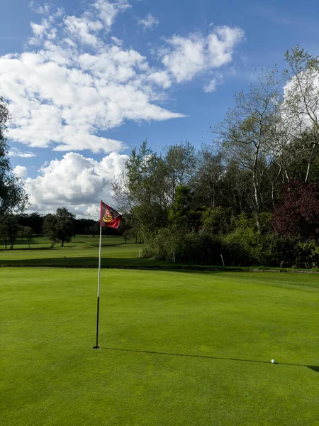 Flag and the hole at golf club blue sky summers day with some clouds