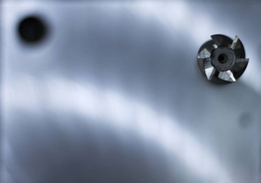 Arka planda bulanık değirmenli yüzeyi olan altı bıçaklı bir kesicinin yüzüne yakın çekim..