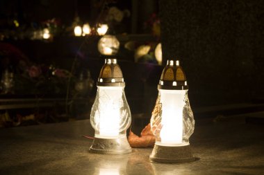 dwa znicze stojce na pycie nagrobnej rozwietlajce ciemn noc na cmentarzu