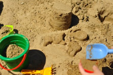 Kum havuzunda çocuk oyunu, renkli kovalar ve kürek kemikleri. Kum kalıpları