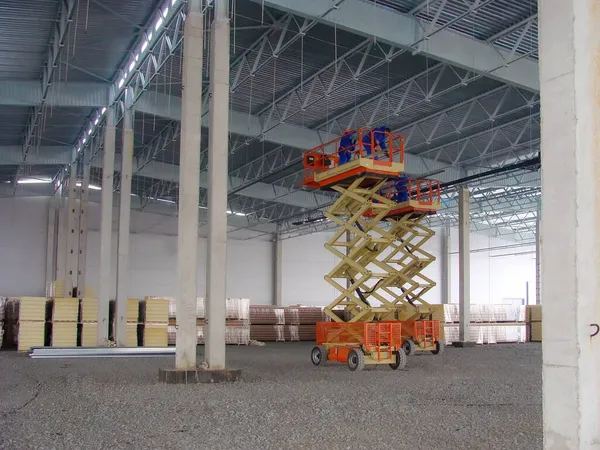 Construcción de un almacén logístico. Elevador de tijera Pekkaniska en funcionamiento a altura. —  Fotos de Stock