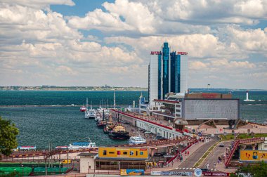 Odessa, Ukrayna. 22 Temmuz 2021. Karadeniz kıyısındaki deniz terminali. Tekneleri ve gemileri olan iskele, cam bina ve deniz feneri.