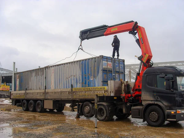 Kiev, Ukraine. January 14. 2011. Truck manipulator, with the help of a crane loads a dirty blue container with a man — Foto de Stock