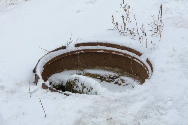Trou d'égout ouvert avec ordures recouvertes de neige en hiver. égouts d'urgence dangereux — Photo