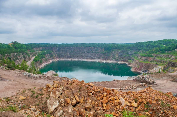 Taşı çıkardıktan sonra suyla dolu büyük bir çukur. Terk edilmiş taş ocağı, dramatik gökyüzü, görkemli manzara.