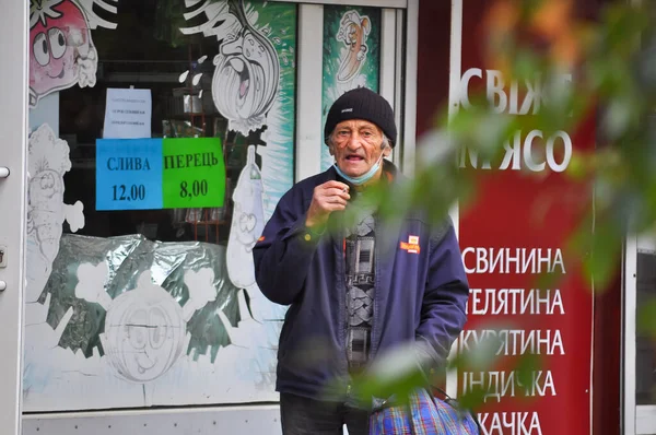 ウクライナのポルタヴァ。9月24日。2021年。老人はタバコを吸うとカメラを見て、路上で非ステージ撮影を報告します。顔にしわ、下の医療用マスク — ストック写真