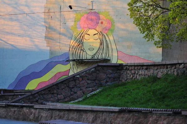 Kropyvnytskyi, Ucrânia. 28 de Abril. 2021. Graffiti na parede, uma jovem menina ucraniana bonita com uma coroa de flores na cabeça e fitas multi-coloridas — Fotografia de Stock