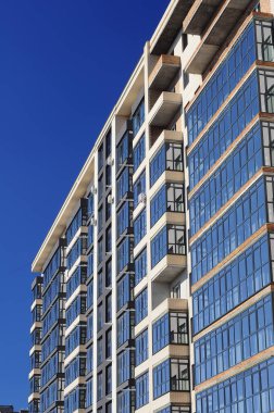 Poltava, Ukrayna. 21 Şubat. 2022 yılı. Bir apartmanın ön cephesinin mimari parçası, tuğla duvarlar ve mavi gökyüzüne karşı camdan balkonlar..