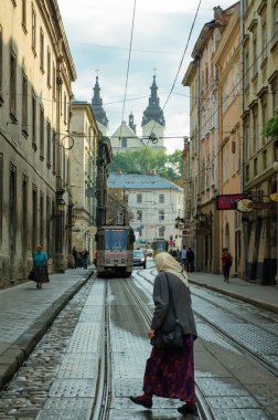 Lviv, Ukrayna. 31 Ağustos. 2014 yılı. Eski kasabada bir cadde, tramvay hattı, kaldırım taşlarının üzerinde yaşlı bir kadın karşıya geçiyor.