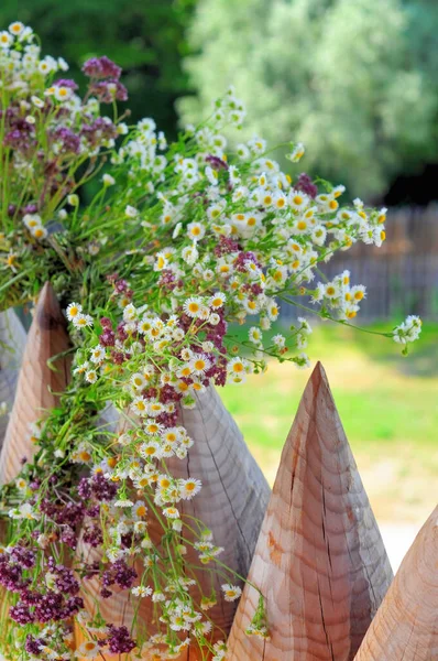 A wreath of wildflowers hangs on pointed wooden pegs of the fence, the holiday of the summer solstice.