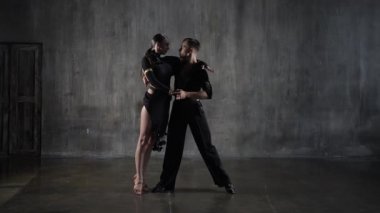 Stüdyo arka planında siyah elbiseli, şehvetli bir dans salonu çifti. Latin dansı yapan profesyonel dansçılar. Hobi dans konsepti. İnsani duygular - aşk ve tutku