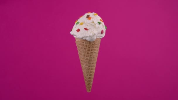 Yummy ice cream in waffle cone. Sweet dessert decorated with colorful sprinkles, rotating soft cream, gelato icecream scoop over pink background — Vídeo de Stock