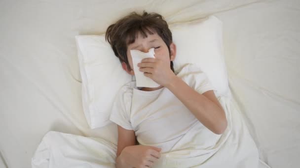 Sick child boy with fever lying on pillow in bed sneezing into tissue. Tired lack of energy preschool kid, temperature, flu symptoms and treatment, children medical healthcare, corona virus symptoms — Vídeo de Stock