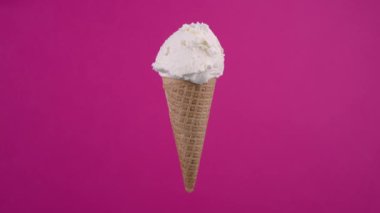 Waffle külahında vanilyalı dondurma. Tatlı tatlı, dönen yumuşak krema, pembe arka planda dondurma kepçesi.