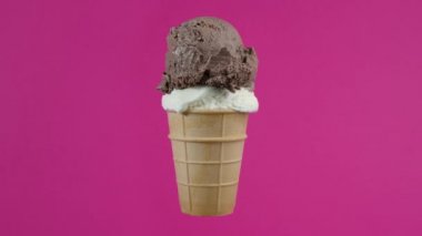 Lezzetli çikolata ve pembe arka planda waffle külahlı vanilyalı dondurma topları. Dönen yumuşak krema, rengarenk arka planda waffle külahında dondurma kepçesi.