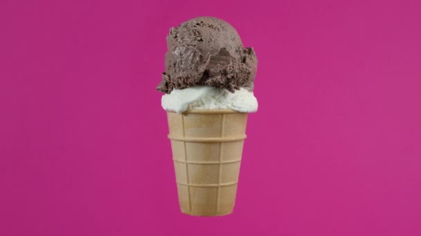 Tasty chocolate and vanilla ice cream balls in waffle cone on pink background. Rotating soft cream, gelato icecream scoop in waffle cone over colorful background — Stockvideo