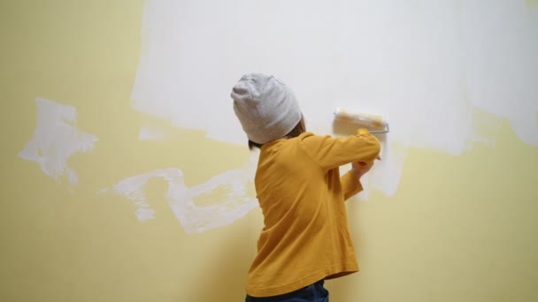 Aranyos kis lány, hogy felújítás, díszítő szoba festmény egy fal egy festék görgő ecset. Összpontosított okos gyerek élvezi kreatív művészeti hobbi tevékenység otthon, gyermekfejlesztés koncepció — Stock videók