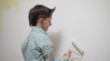 Hoş, komik okul çocuğu tadilat yapıyor, boya fırçasıyla duvarı boyuyor. Odaklanmış akıllı çocuk evde yaratıcı sanat hobisi, çocuk gelişimi konsepti