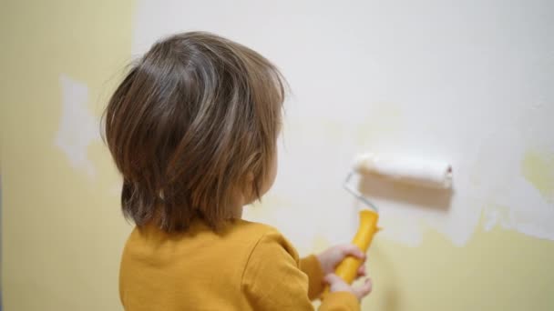 Tadilat yapan sevimli bir bebek, boya fırçasıyla duvarı boyayan dekorasyon odası. Odaklanmış akıllı çocuk evde yaratıcı sanat hobisi, çocuk gelişimi konsepti — Stok video