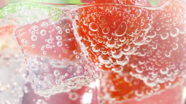 Savoureux cocktail de limonade ou de mojito aux fraises rafraîchissantes avec glaçons et feuilles de menthe fraîches. Tranches de baies en tonique pétillant pétillant avec bulles, jus de fruits boisson gazeuse ou boisson gazeuse — Video