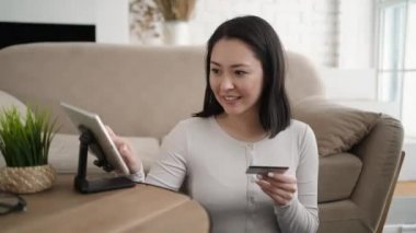 Karışık ırk Asyalı kadın müşteriler e-ticaret e-mağazaları üzerinden para harcarlar, kolay yöntemlerle internetten satın alırlar, kredi kartlarını tablet bilgisayar kullanarak öderler. Modern teknoloji, güvenli ödeme, indirim konsepti.