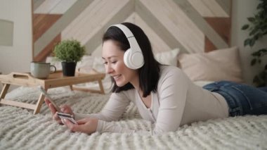 Karışık ırk Asyalı kadın müşterinin elinde banka kartı ve akıllı telefon numaraları var. İnternetten ya da rezervasyon otelinden satın alıyorlar. Ev hanımı yemek teslimatını öder, kolay elektronik ödeme kavramını güvence altına alır.