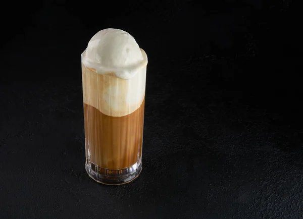 Minuman kopi bebas laktosa modern atau koktail dengan es krim dan susu almond. Macchiato dalam gelas tinggi dengan latar belakang gelap. Cafe minuman dilapisi dengan susu dalam gelas minum tinggi. Salin ruang Stok Gambar Bebas Royalti