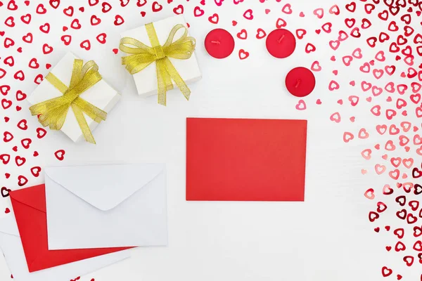 El yapımı kağıt hediye kutuları, zarflar ve mumların bileşimi. Kalpleri beyaz ahşap bir masaya yerleştirir. Doğum günü için içerik, Sevgililer Günü, Kadınlar Günü. Düz yat, üst görünüm, kapat, boşluğu kopyala